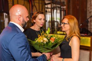 mężczyzna i kobieta wręczają kwiaty drugiej kobiecie