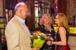 dwie kobiety i mężczyzna z kwiatami