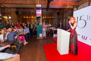 kobieta mówi do mikrofonu, goście słuchają