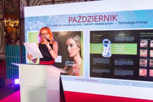 kobieta mówi do mikrofonu, w tle rzutnik